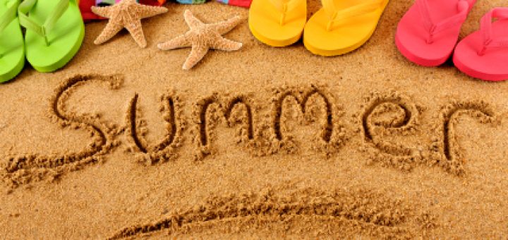 The word Summer written on a sandy beach, with beach towel, starfish and flip flops (studio shot - warm color and directional light are intentional).  Note: extreme wide angle shot with curvature of field and focus on the word Summer.